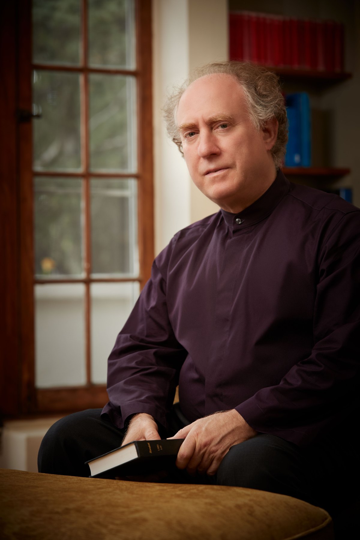 Jeffrey Kahane seated with a book beside a window